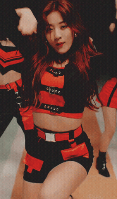 A Woman In A Red Top And Black Shorts Is Dancing With Her Hands In The Air GIF