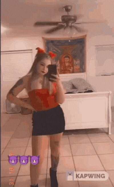 A Woman In A Red Top And Black Skirt Is Taking A Picture Of Herself In A Mirror . GIF