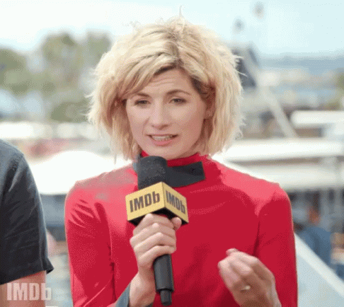 A Woman In A Red Top Is Holding A Microphone That Says Imdb On It GIF