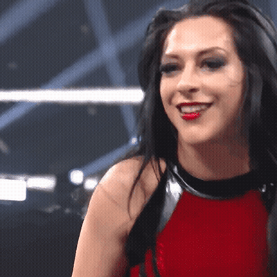 A Woman In A Red Top Is Smiling And Looking At The Camera GIF