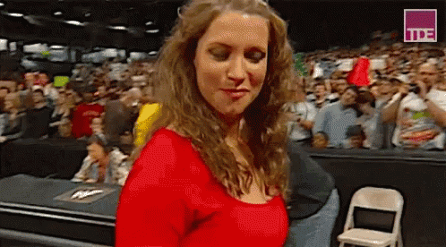 A Woman In A Red Top Is Standing In Front Of A Crowd Of People . GIF