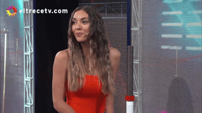 A Woman In A Red Top Is Standing In Front Of A Screen With Eltrecetv.com Written On It GIF