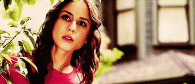 A Woman In A Red Top Is Standing In Front Of A Window . GIF
