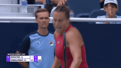 A Woman In A Red Top Stands In Front Of A Scoreboard That Says " Match Point # 10 " GIF