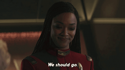 A Woman In A Red Uniform Says " We Should Go " In White Letters GIF