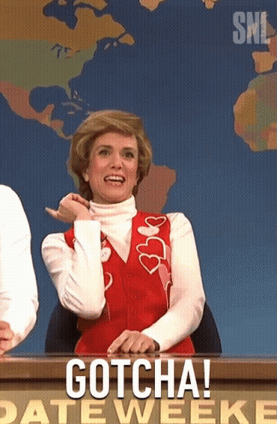 A Woman In A Red Vest Is Sitting At A Desk With The Words Gotcha On It GIF