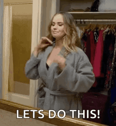 A Woman In A Robe Is Standing In Front Of A Mirror And Saying `` Lets Do This ! '' GIF