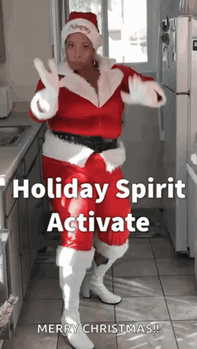 A Woman In A Santa Costume Is Dancing In A Kitchen . GIF