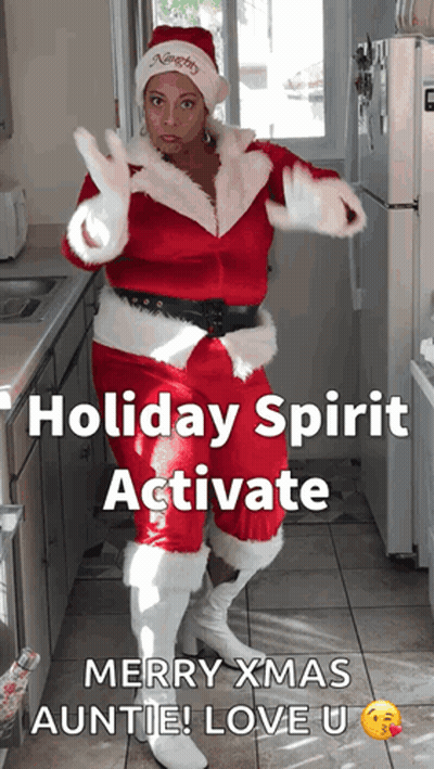 A Woman In A Santa Suit Is Dancing In A Kitchen GIF