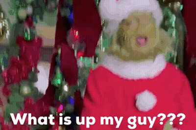 A Woman In A Santa Suit Is Standing In Front Of A Christmas Tree And Says What Is Up My Guy GIF