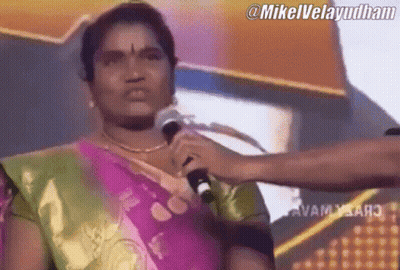 A Woman In A Sari Is Holding A Microphone In Front Of Her Face .. GIF