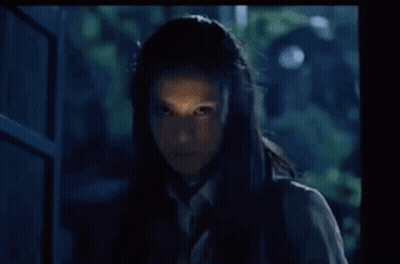 A Woman In A School Uniform And Tie Is Standing In Front Of A Door . GIF
