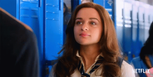 A Woman In A School Uniform And Tie Is Standing In Front Of Blue Lockers With A Netflix Logo In The Corner . GIF