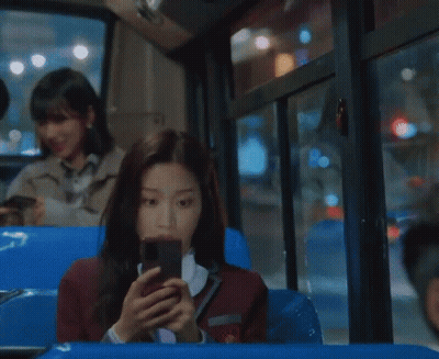 A Woman In A School Uniform Is Looking At Her Cell Phone GIF