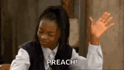 A Woman In A School Uniform Is Sitting At A Table With Her Hands In The Air And Saying Preach . GIF