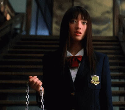 A Woman In A School Uniform Is Standing In Front Of Stairs . GIF