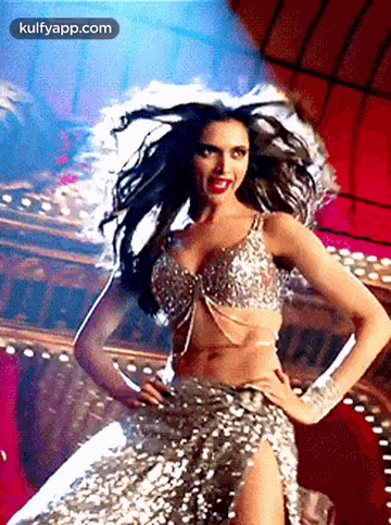 A Woman In A Sequined Dress Is Dancing In Front Of A Crowd . GIF