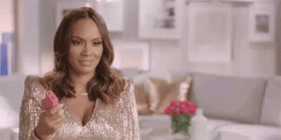 A Woman In A Sequined Dress Is Holding A Pink Object . GIF