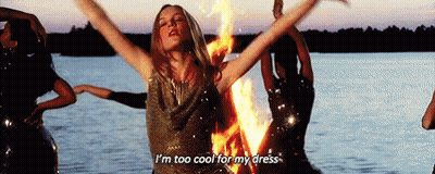 A Woman In A Sequined Dress Is Standing In Front Of A Fire And Says I 'M Too Cool For My Dress GIF