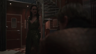 A Woman In A Sequined Dress Stands Next To A Man GIF