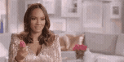 A Woman In A Sequined Top Is Holding A Pink Object In Her Hand . GIF