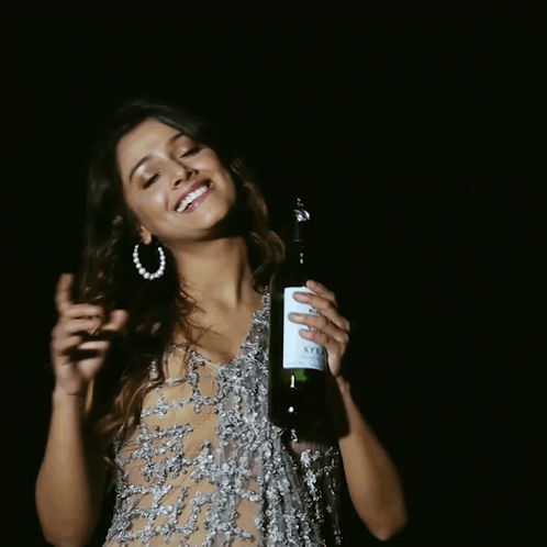 A Woman In A Sheer Dress Is Holding A Bottle Of Wine With A Label That Says ' A ' On It GIF