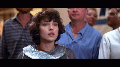 A Woman In A Silver Armor Stands In Front Of A Crowd Of People GIF