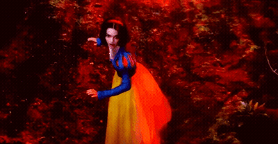 A Woman In A Snow White Costume Is Standing In A Red Forest . GIF