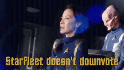 A Woman In A Star Fleet Uniform Stands Next To A Man In A Star Trek Uniform GIF