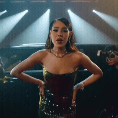 A Woman In A Strapless Dress Is Standing In Front Of A Car On A Stage . GIF