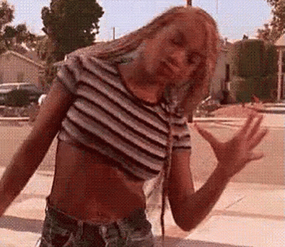 A Woman In A Striped Crop Top And Shorts Is Dancing On The Street . GIF