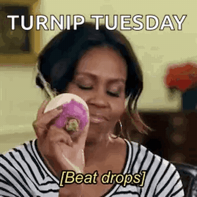 A Woman In A Striped Shirt Is Holding A Purple Radish In Her Hand . GIF