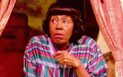 A Woman In A Striped Shirt Is Making A Funny Face While Sitting In Front Of A Window . GIF