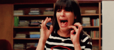 A Woman In A Striped Shirt Is Screaming And Holding A Cell Phone In Her Hand . GIF