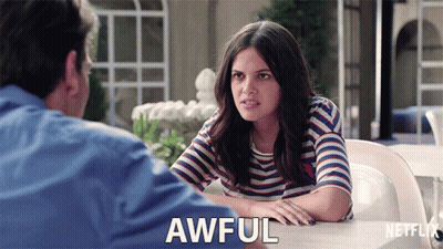 A Woman In A Striped Shirt Is Sitting At A Table With A Man And Says Awful In Front Of Her GIF