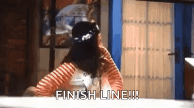 A Woman In A Striped Shirt Is Sitting At A Table With Her Hands On Her Head And Says `` Finish Line '' . GIF