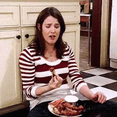 A Woman In A Striped Shirt Is Sitting On The Floor Eating Food . GIF