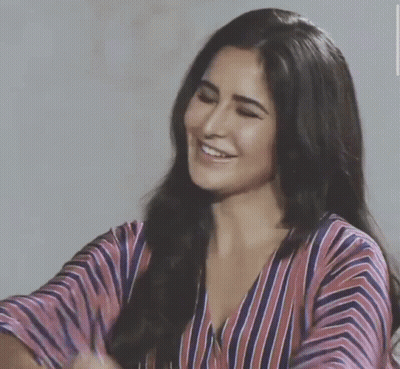 A Woman In A Striped Shirt Is Smiling And Looking Down GIF