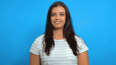 A Woman In A Striped Shirt Is Smiling While Holding A Cardboard Trophy GIF