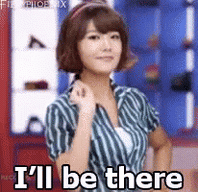 A Woman In A Striped Shirt Is Standing In Front Of A Sign That Says I 'Ll Be There GIF
