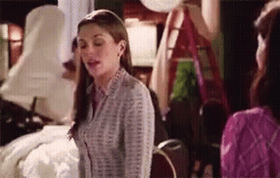 A Woman In A Striped Shirt Is Standing Next To Another Woman In A Pink Shirt . GIF
