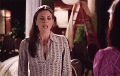A Woman In A Striped Shirt Is Talking To Another Woman In A Living Room . GIF