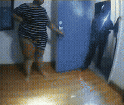 A Woman In A Striped Shirt Stands In Front Of A Door GIF
