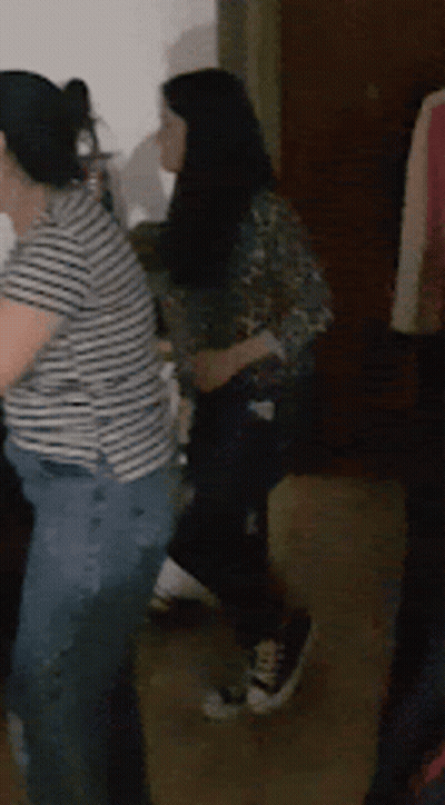 A Woman In A Striped Shirt Stands Next To Another Woman In Jeans GIF