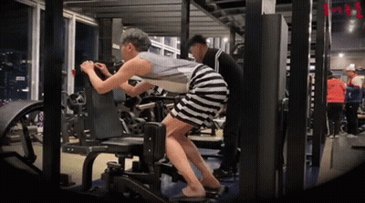 A Woman In A Striped Skirt Is Doing Exercises In A Gym GIF