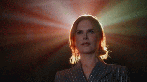A Woman In A Striped Suit Is Looking Up At The Sun GIF