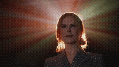 A Woman In A Striped Suit Stands In Front Of A Red Light GIF