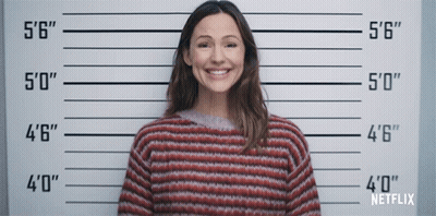 A Woman In A Striped Sweater Is Smiling In Front Of A Police Line Up That Says Netflix GIF