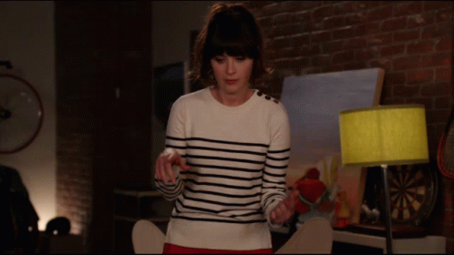 A Woman In A Striped Sweater Stands In Front Of A Painting GIF
