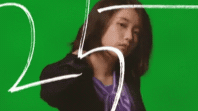 A Woman In A Suit And A Purple Shirt Is Standing In Front Of A Green Screen . GIF